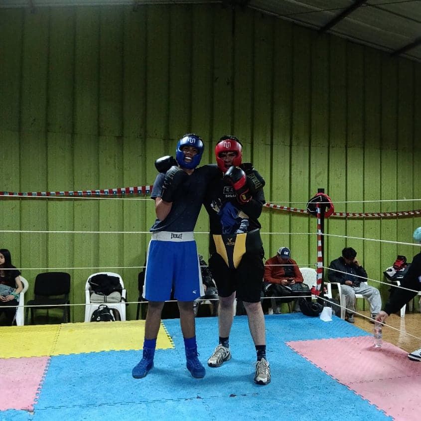 Dos boxeadores con cabezal posando en el ring del gimnasio antes del sparring