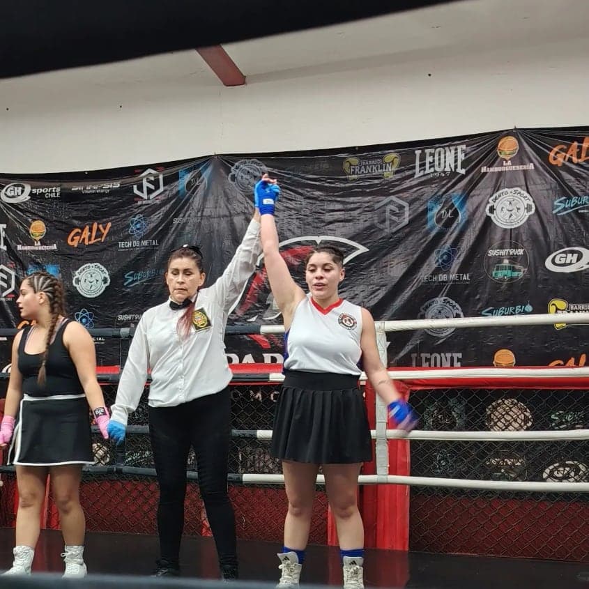 La árbitra levanta la mano de una boxeadora del club tras ganar su combate