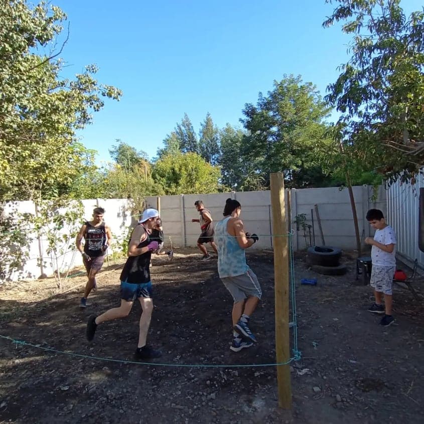 Entrenamiento al aire libre en un patio de tierra, con un ring hecho de cuerdas y postes